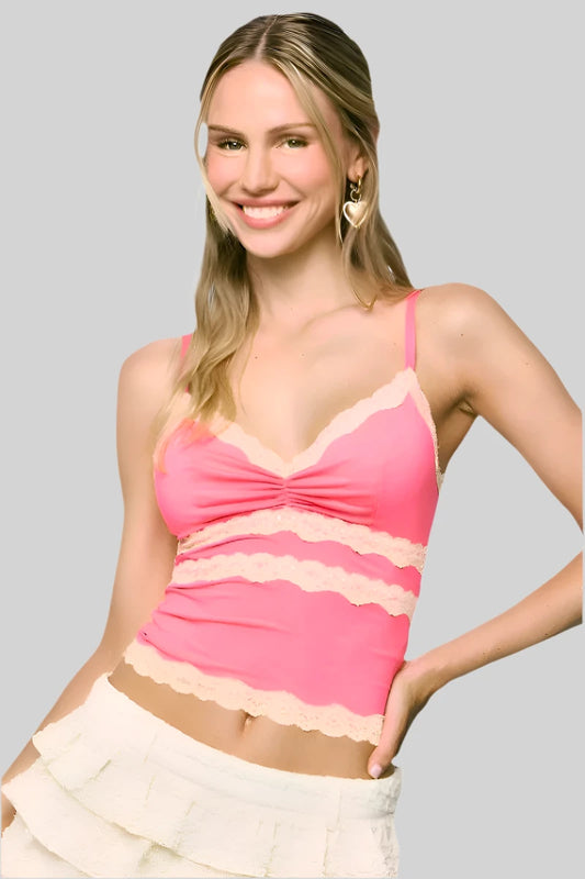 Woman wearing a pink top with lace details against a gray background